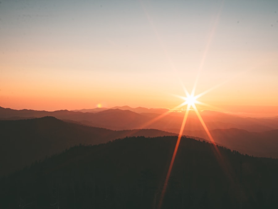 Sharp golden-hour light rays over layered mountain ridgelines